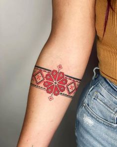 a woman's arm with a red and black cross tattoo on the left forearm