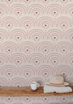 a hat and cup are sitting on a shelf in front of a wallpapered background