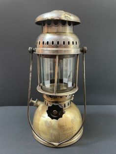 an old fashioned brass lantern on a gray surface with the light turned on and showing