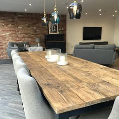 a wooden table surrounded by grey chairs in a room with brick walls and flooring