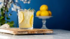 a glass filled with lemonade sitting on top of a cutting board next to some lemons