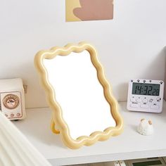 a mirror sitting on top of a white desk next to a clock and alarm clock