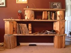 a bookshelf made out of wooden logs in a living room with pictures on the wall