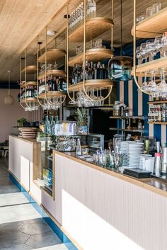 a bar with lots of bottles and glasses hanging from it's ceiling above the counter