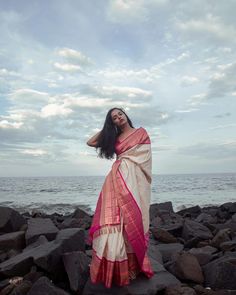 a woman standing on rocks near the ocean