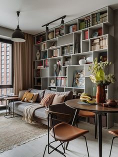 a living room filled with lots of furniture and bookshelves next to a window