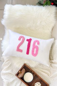 a white pillow with the number twenty six on it next to a candle and some cookies