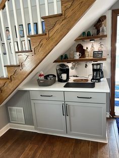 a kitchen under the stairs with coffee maker and other items on top of it's cabinets