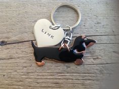 a black and brown dog keychain with a heart shaped tag on it's side