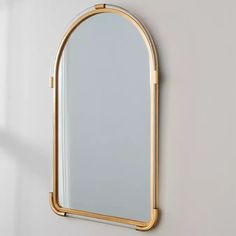 a mirror hanging on the wall with a gold frame and an oval shaped mirror above it