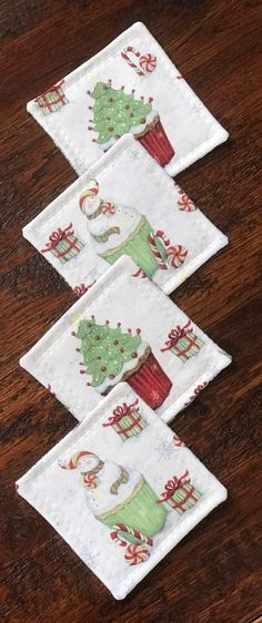 three pieces of fabric with christmas designs on them sitting on a wooden table next to each other