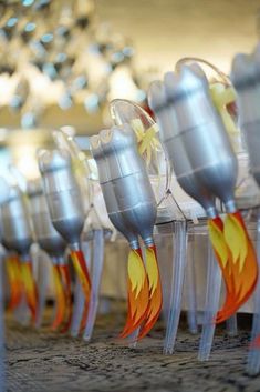 several silver vases with yellow and red designs on them are lined up in rows