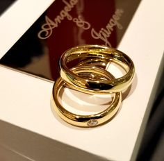 two gold rings sitting on top of a white box