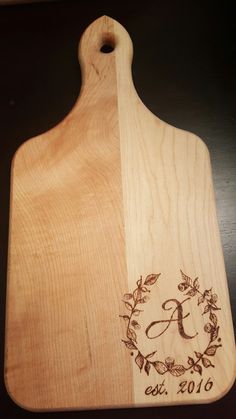 a wooden cutting board with a monogrammed design on it