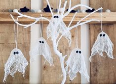 three white halloween decorations hanging from a tree