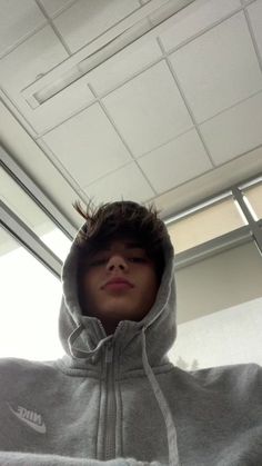 a young boy wearing a nike hoodie in an office building with his eyes closed