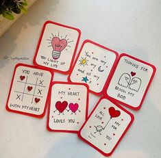 four red and white coasters with handwritten words on them sitting on a table