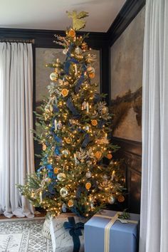 a decorated christmas tree in a living room with blue and white presents under the tree