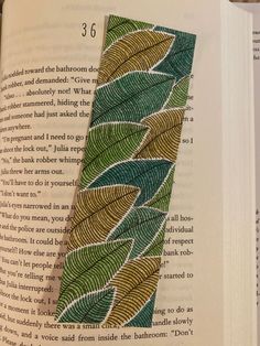 an open book with green leaves on it