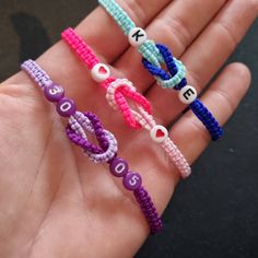 three different colored bracelets are held in someone's hand with the word love spelled on them