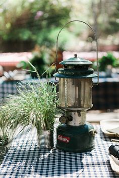 an old fashioned lantern is on top of a table with plates and utensils