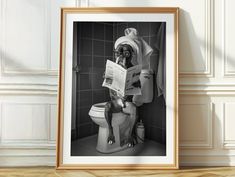 a black and white photo of a dog sitting on a toilet reading a book in a bathroom