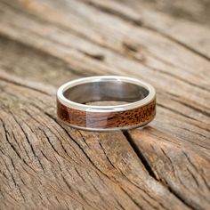 a wedding ring with wood inlays sits on a wooden surface