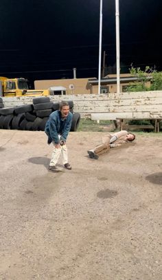 two men standing in front of a pile of tires and one laying on the ground