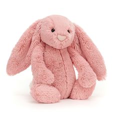 a pink stuffed rabbit sitting on the ground