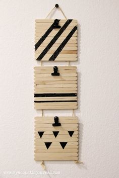 two pieces of wood with black and white designs hanging on the wall next to each other