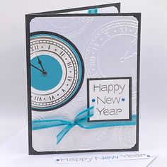 a new year's card with a clock on the front and blue ribbon around it