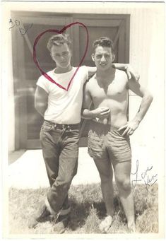 two men standing next to each other in front of a door with a heart on it