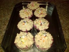 cupcakes with white frosting and sprinkles on a black tray