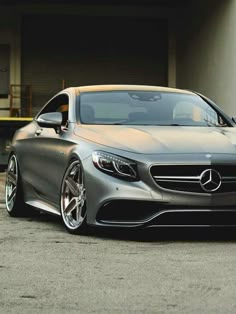 the front end of a silver mercedes s - class coupe parked in front of a garage