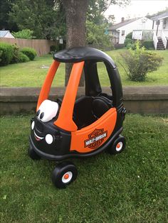 an orange and black toy car sitting in the grass