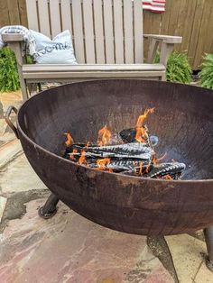 a fire pit sitting on top of a patio next to a wooden table and chairs