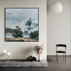 a painting hanging on the wall next to a chair and vase with plants in it