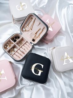 four different colored jewelry cases sitting on top of a white bed next to each other