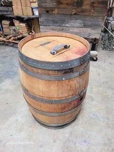 an old wooden barrel sitting on the floor next to other wood and metal items in a storage area