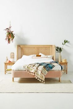 a bed sitting on top of a white floor next to a plant