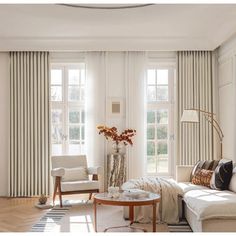 a living room filled with furniture and windows covered in white drapes next to a wooden floor