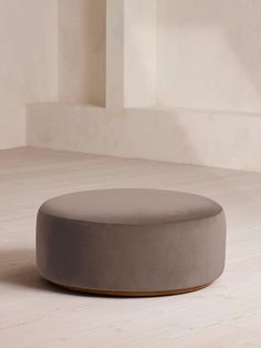 a round ottoman sitting on top of a white floor