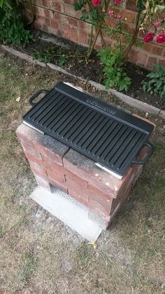 a grill sitting on top of a brick box in the grass