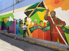 a man standing in front of a mural on the side of a building with people holding flags