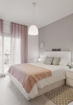 a bedroom with a bed, nightstands and pink drapes on the windowsill