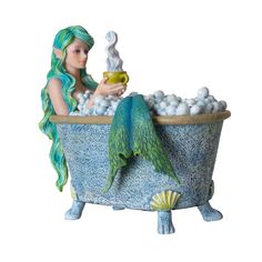 a statue of a mermaid sitting in a bathtub filled with white balls and holding a cup