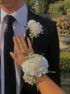 a man in a suit and tie holding flowers next to a woman's hand