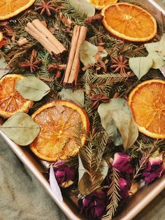 an assortment of dried oranges and herbs on a tray with cinnamon sticks, star anise