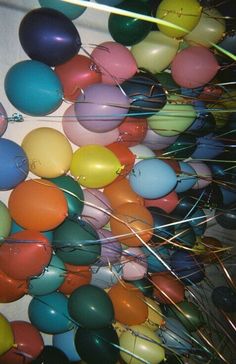 many colorful balloons are in the air with some pins sticking out of it's sides