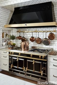 a stove top oven sitting inside of a kitchen next to white cupboards and drawers